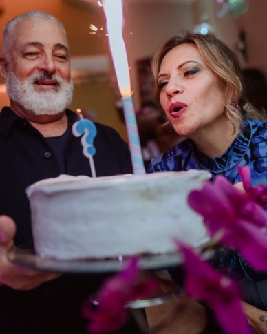 Casal soprando a vela do bolo de aniversário