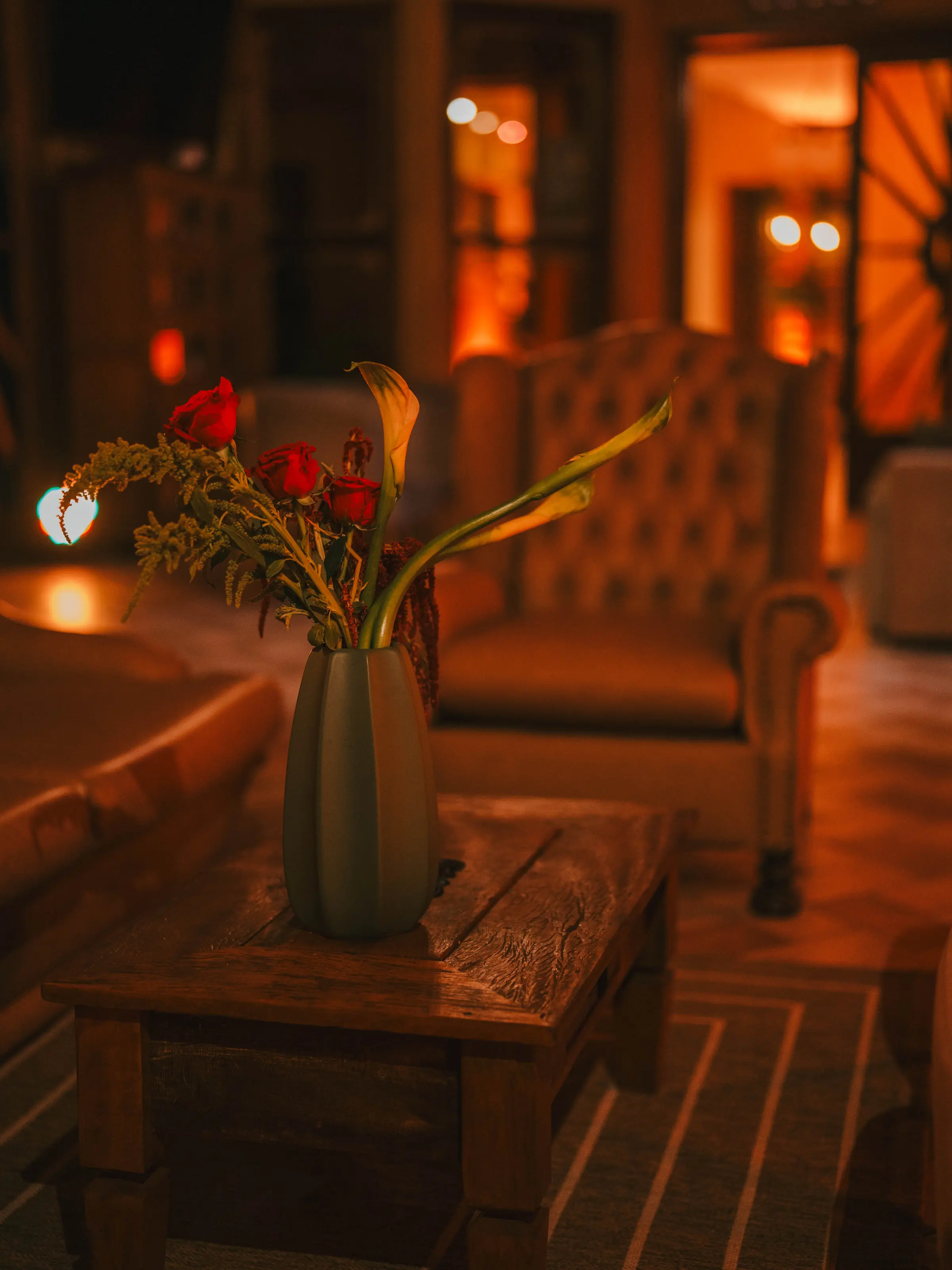Poltrona de veludo e arranjo de flores vermelhas no salão iluminado