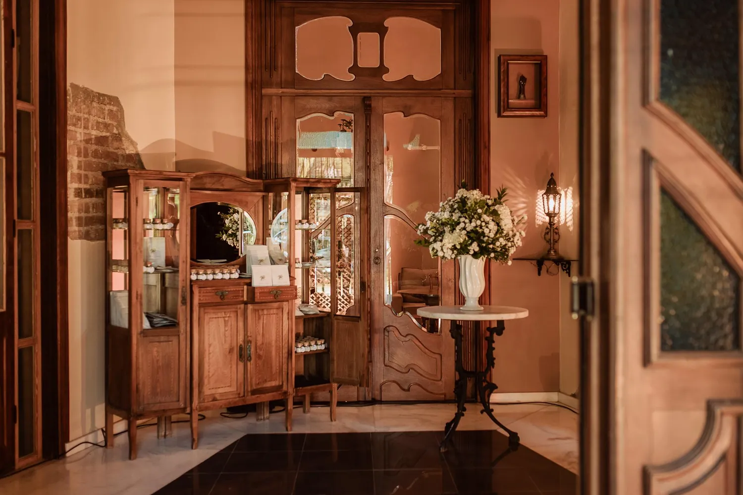 Entrada com móveis antigos, arranjo de flores brancas e porta de madeira